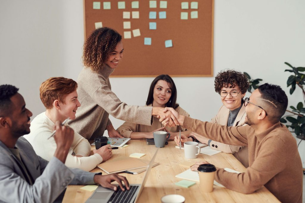 Man and woman shaking hands at a group table meeting